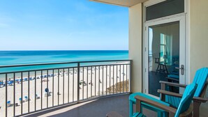 Un balcón con vista a la playa, una puerta y una silla azul.