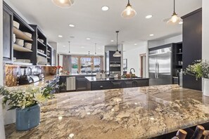 A modern kitchen with granite countertops, stainless steel appliances, and pendant lighting.