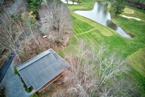 A house with a sloped roof, surrounded by a pond and a golf course.