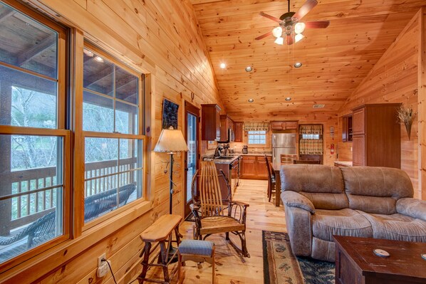 A wooden cabin interior with a dining area, a sofa, and a kitchen.
