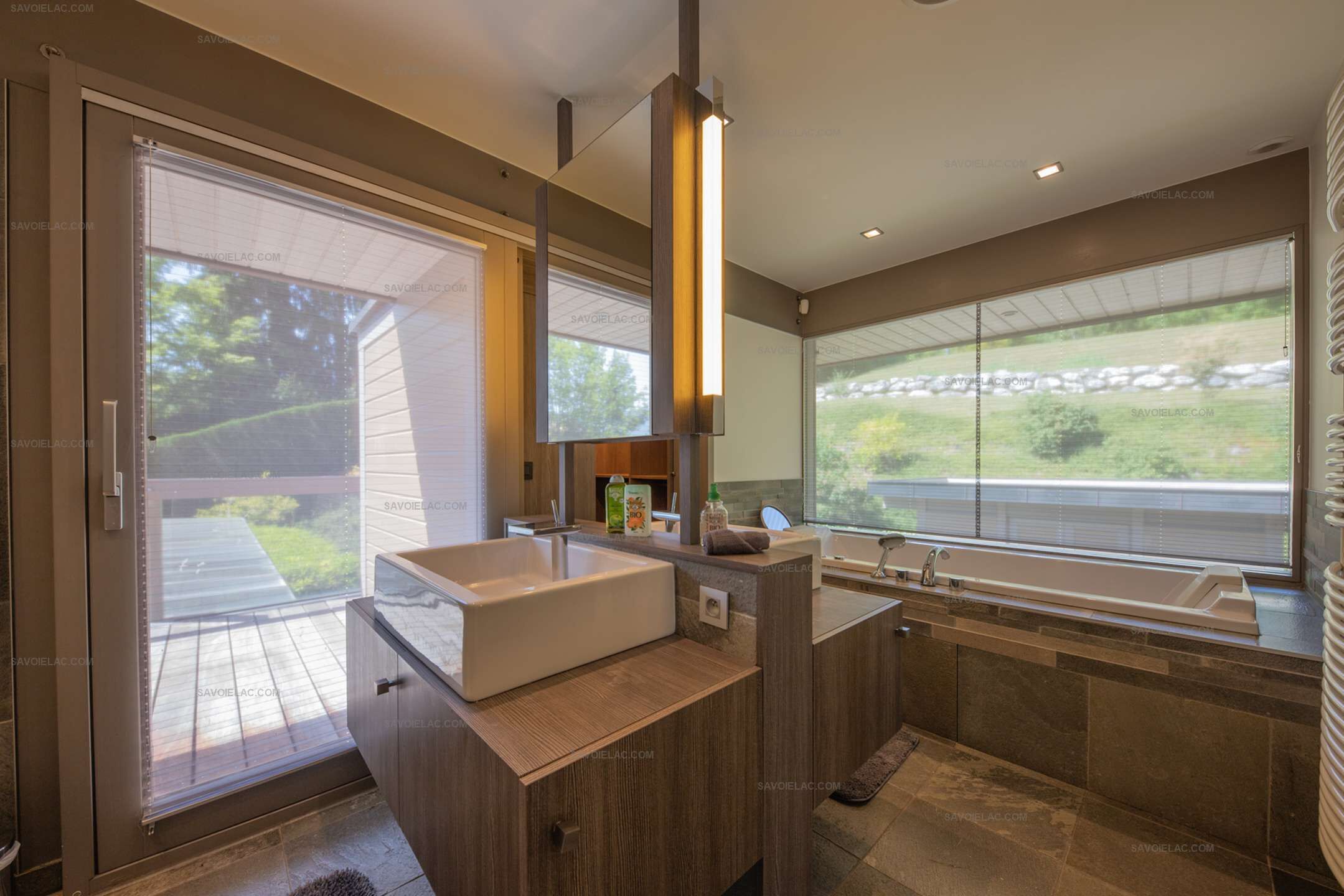 A modern bathroom with a large sink, a mirror, and a window providing a view of the outdoors.