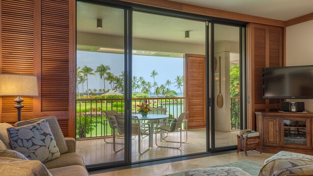 A modern living room with a sofa, a television, and a dining area with a table and chairs.