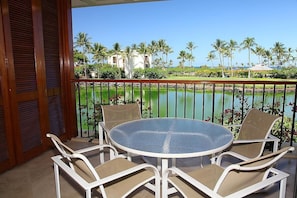 Enjoy a tranquil view of the water from this balcony with a table and chairs.
