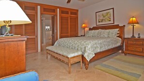 A bedroom with a bed, bedside tables, a chair, a wardrobe, and a door leading to another room.