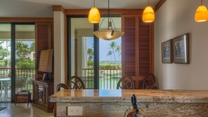 A kitchen with a granite countertop, a stove, and overhead pendant lights.