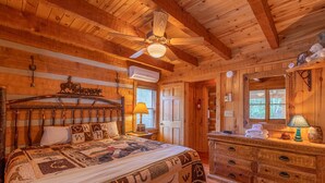 A wooden cabin bedroom with a bed, dresser, and ceiling fan. - Altitude Adjustment - Seven Devils cabin with Hot Tub, Pet Friendly, Fireplace (Seven Devils)