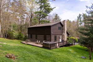 A cabin with a deck, surrounded by trees. - Hemlock Hideaway: Quiet Neighborhood Cabin Near Boone & Blowing Rock with Firepit, Yard, & Hot Tub! (Boone)