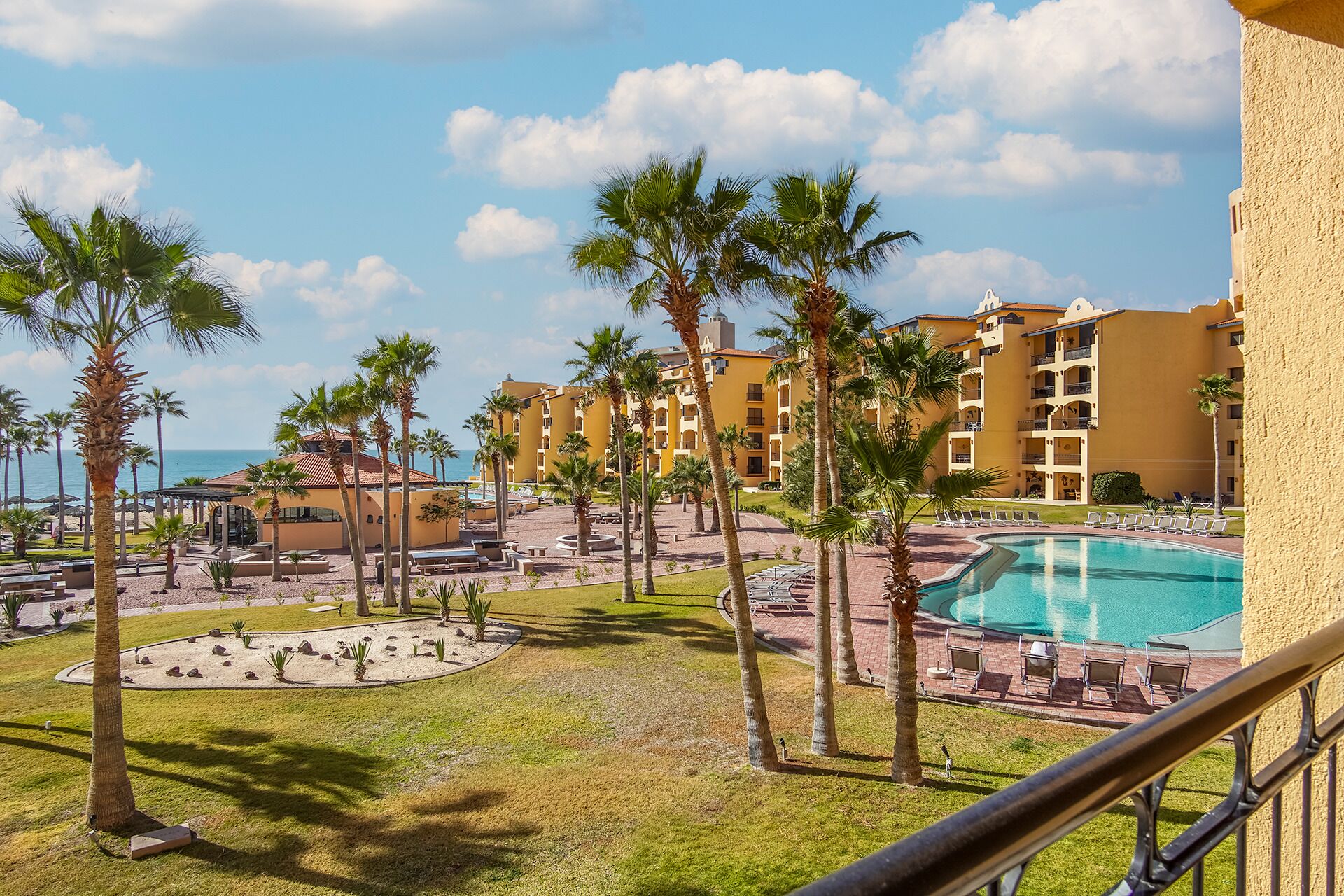 Een resort met een zwembad, palmbomen en uitzicht op de oceaan.