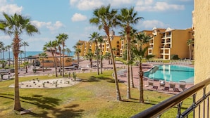 Un resort con piscina, palmeras y vista al océano.