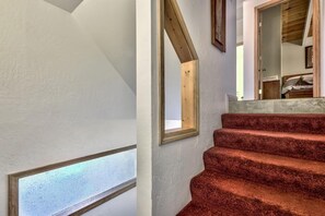 Eine Treppe mit rotem Teppich führt zu einem Schlafzimmer mit Holzboden.