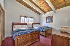 Ein Schlafzimmer mit zwei Holzbetten, einem Fenster, einem gerahmten Bild und einer Holzkommode.