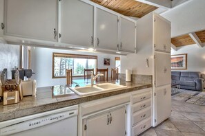 A kitchen with white cabinets, a granite countertop, and a built-in dishwasher.