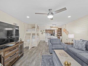 A modern living room with a TV, sofa, coffee table, and a ceiling fan.