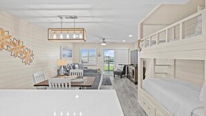 A modern interior with bunk beds, a dining area, and a kitchen. - 103 Beach Level, Beautifully Decorated, Ground Floor with FREE Beach Service (Destin)