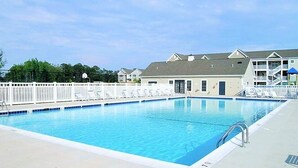 Una piscina rettangolare con superficie d'acqua blu trasparente, circondata da una recinzione bianca.