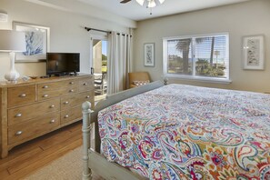 A bedroom with a bed, a TV, a dresser, a chair, and a window with blinds. - Sandy Key 122:  2 BR/2 BA Perdido Key, FL Beachfront Condo, On-Site Rental Office, Sleeps 6 (Pensacola)