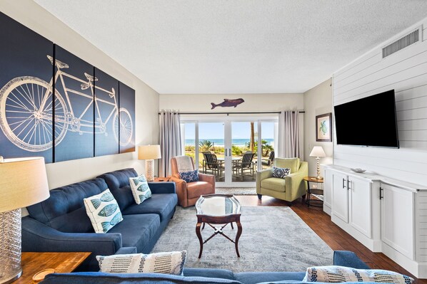 A living room with a sofa, chairs, a coffee table, a TV, and a view of the ocean. - Sandy Key 122:  2 BR/2 BA Perdido Key, FL Beachfront Condo, On-Site Rental Office, Sleeps 6 (Pensacola)