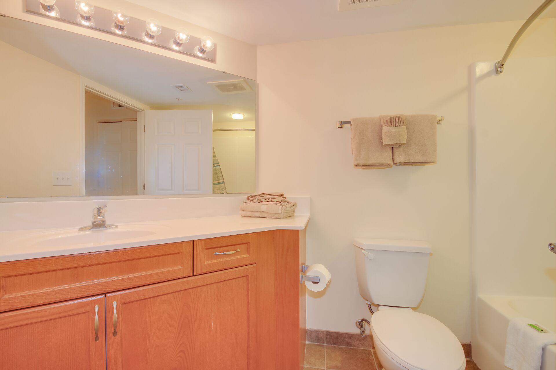 Un baño con tocador, lavamanos, espejo con luces, inodoro y zona de ducha.