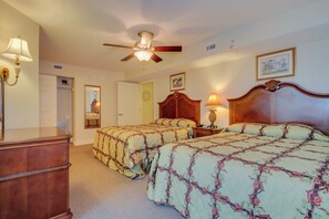 A hotel room with two beds, a wooden dresser, a ceiling fan, and a nightstand with a lamp. - Spacious oceanfront, corner unit + Free Attraction Tickets! (North Myrtle Beach)
