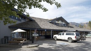 A building with a sloped roof, a covered outdoor seating area, and a parked SUV with bicycles. - Nestle into the peace and quiet of the Aspens (Wilson)