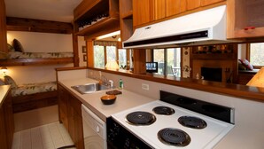 A compact kitchen with wooden cabinets, a white stove, and a sink. - Nestle into the peace and quiet of the Aspens (Wilson)