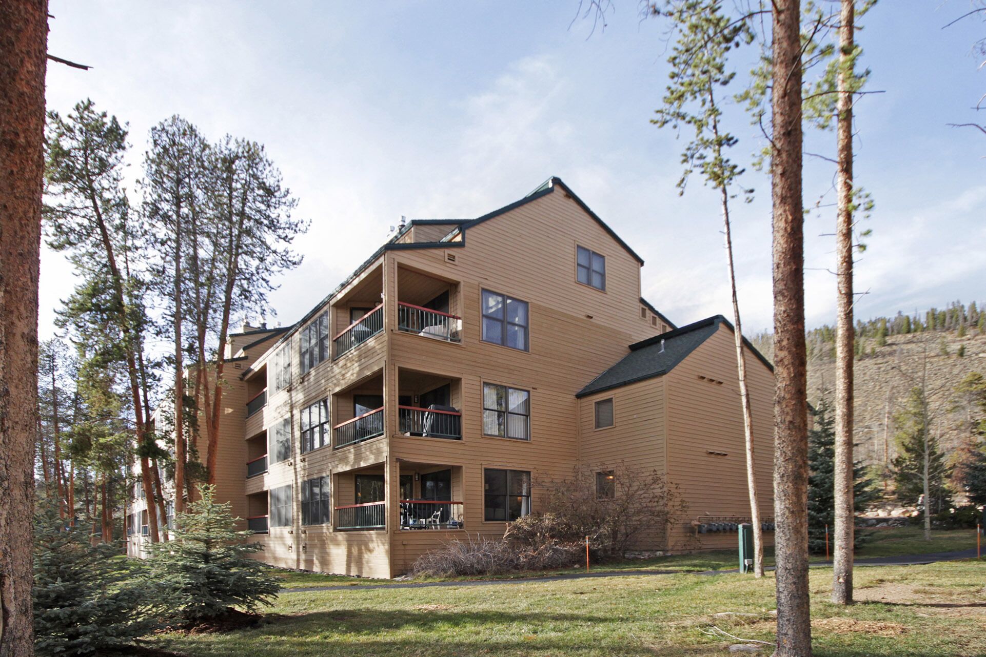 A multi-story building with balconies, surrounded by trees.