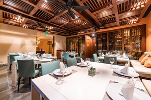 Enjoy a refined dining experience with beautifully set tables, comfortable seating, and a wine display.