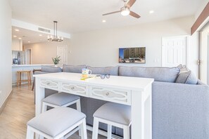A modern kitchen with a white countertop, a built-in seating area with a gray sofa and matching stools, and a ceiling fan.