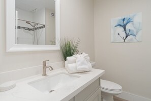 Ein Badezimmer mit einem weißen Waschbecken, einem Spiegel, einer Toilette und einem Wandbild.