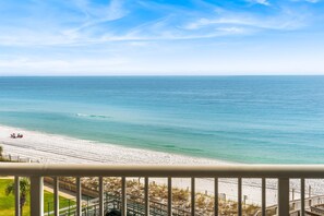 Blick auf einen Strand vom Balkon mit Geländer, feiner Sand und das Meer.