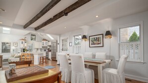 Una cocina amplia con comedor, vigas de madera en el techo y vistas al exterior a través de grandes ventanales.