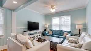 A living room with a television, two sofas, a coffee table, and a ceiling fan. - Newly Refurbished - Beach House with pool & hot tub +Free Attraction Tickets! (North Myrtle Beach)
