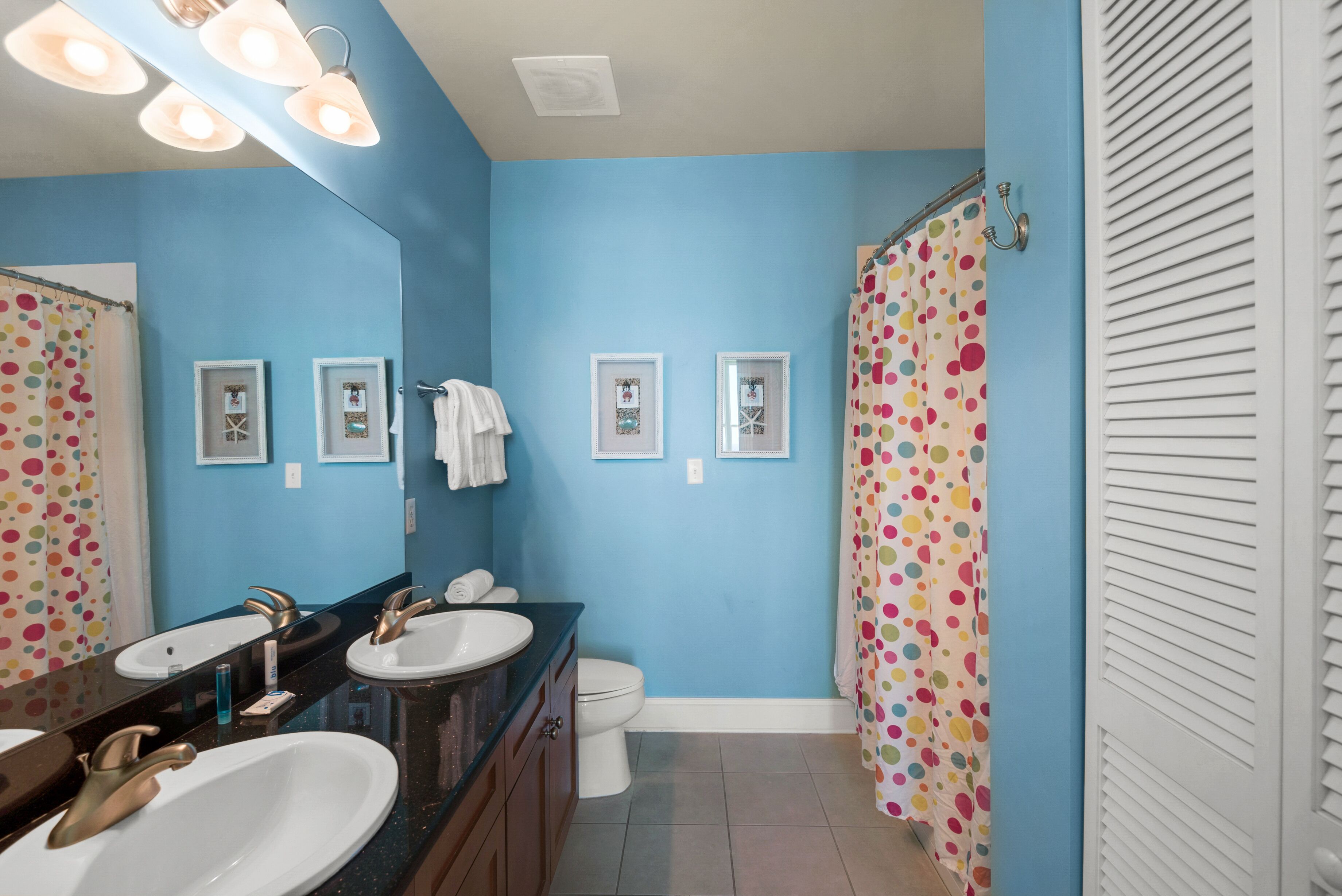 A bathroom with two sinks, a toilet, and a shower curtain with a polka dot pattern.