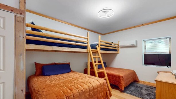 A room with bunk beds, a ladder, a desk, and a window with blinds. - A Sunrise Summit - 4BR, 3BA - Hot Tub, Pets (Seven Devils)