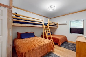 Ein Zimmer mit Etagenbetten, einer Himmelsleiter, einem Schreibtisch und einem Fenster mit Jalousien.