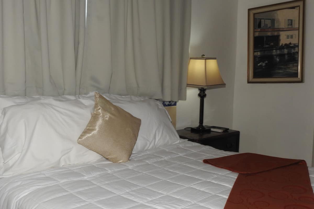 Une chambre d’hôtel avec un lit, une table de chevet avec une lampe et un tableau encadré au mur.