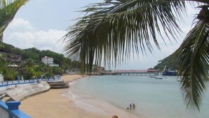 A beach with a blue railing, a sandy shore, and a calm sea. - Agua Sol Villa (Taboga)