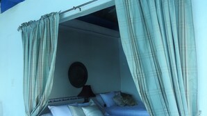 A bedroom with a bed, curtains, a lamp, and a wall-mounted round mirror. - Agua Sol Villa (Taboga)