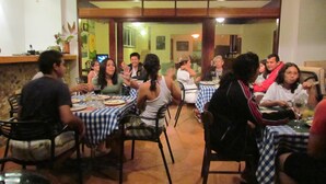 A restaurant with patrons seated at tables with blue and white checkered tablecloths. - Agua Sol Villa (Taboga)