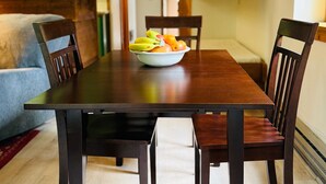 A dining table with a bowl of fruit, surrounded by wooden chairs in a room with wooden beams and a green wall. - JHRL - Aspens Tamarack 611, perfect for a couple or single vacationers (Wilson)
