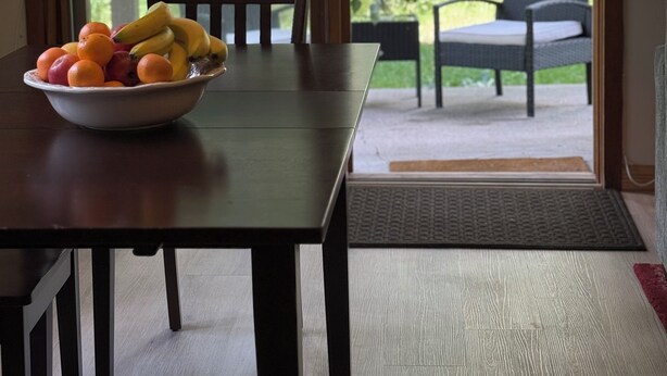A dining table with a bowl of fruit, a chair, and a view of a garden through glass doors. - JHRL - Aspens Tamarack 611, perfect for a couple or single vacationers (Wilson)
