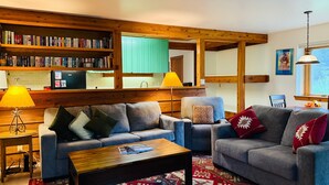 A cozy living room with two sofas, a coffee table, and a bookshelf filled with books. - JHRL - Aspens Tamarack 611, perfect for a couple or single vacationers (Wilson)