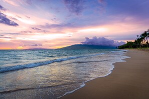 A beach with waves, a sunset, and palm trees. - Beachfront Bliss , cancellation 8/15 to 8/22. need a dry place in the storm? (Kihei)