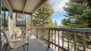 A wooden deck with outdoor seating and a view of a beach and trees. - JHRL - Rendezvous B3, Comfortable Slope-side Condo, Hot tub next door (Teton Village)