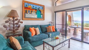 A living room with a sofa, a glass coffee table, and a painting on the wall.