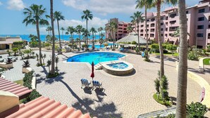A resort pool area with a hot tub, lounge chairs, and palm trees.