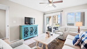 Ett vardagsrum med en tv, ett blått skåp, ett soffbord och två soffor.
