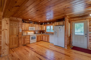 Una cabaña de madera con cocina equipada con microondas, estufa, refrigerador y lavaplatos.