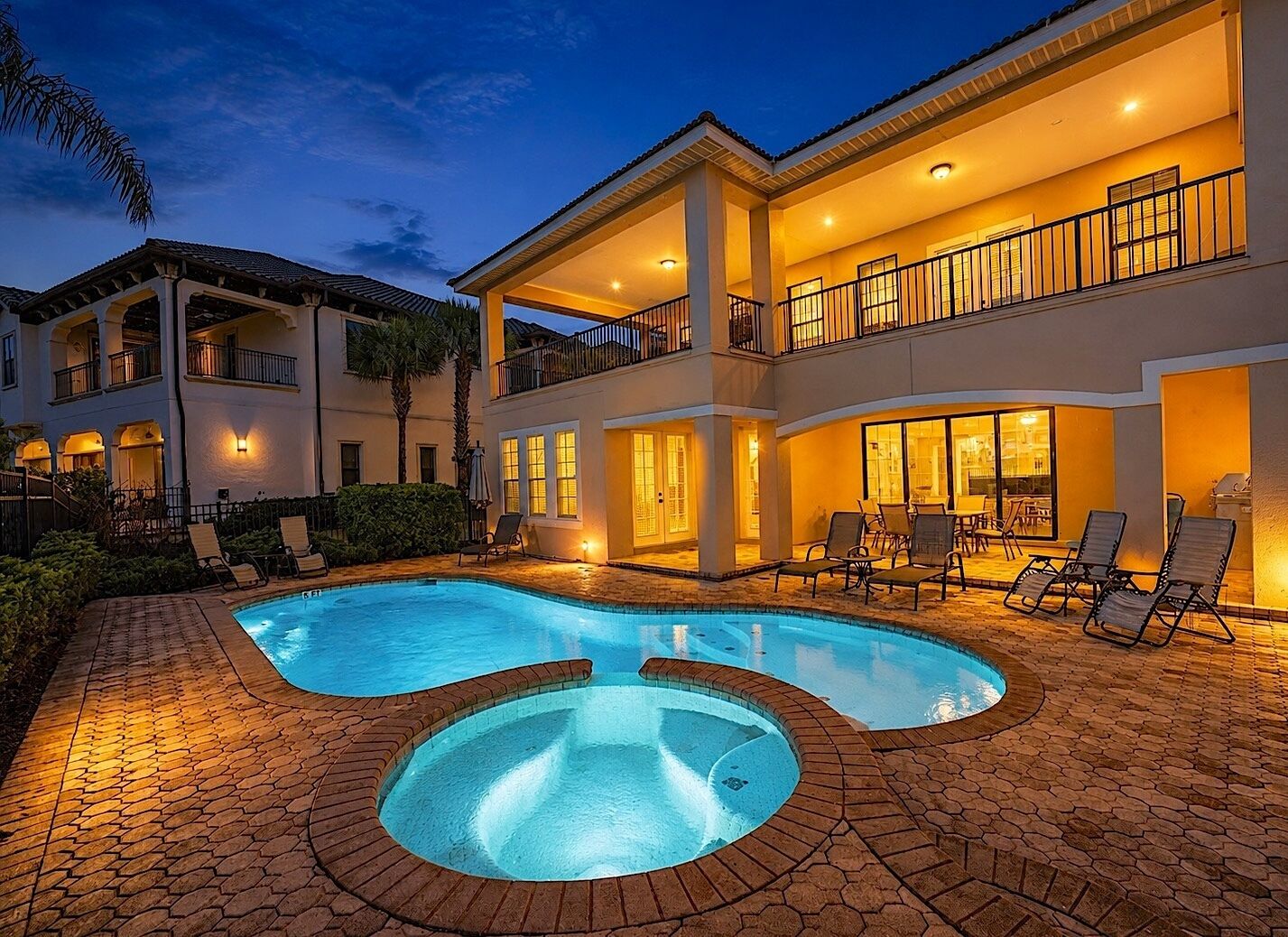 A two-story house with a swimming pool and outdoor seating.