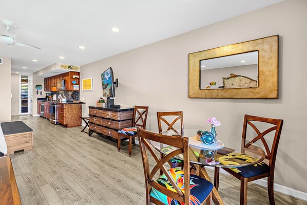 Una habitación espaciosa con una zona de cocina, muebles de madera y un cuadro grande en la pared.